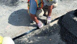 Man applying a repair strip to a highway