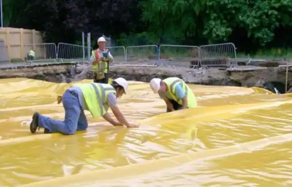 Men applying Visqueen membrane onto ground